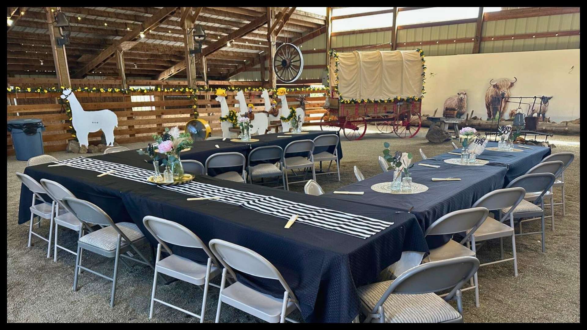 decorated event barn with long tables, black tablecloths, floral centerpieces, and rustic western décor at a North Idaho ranch
