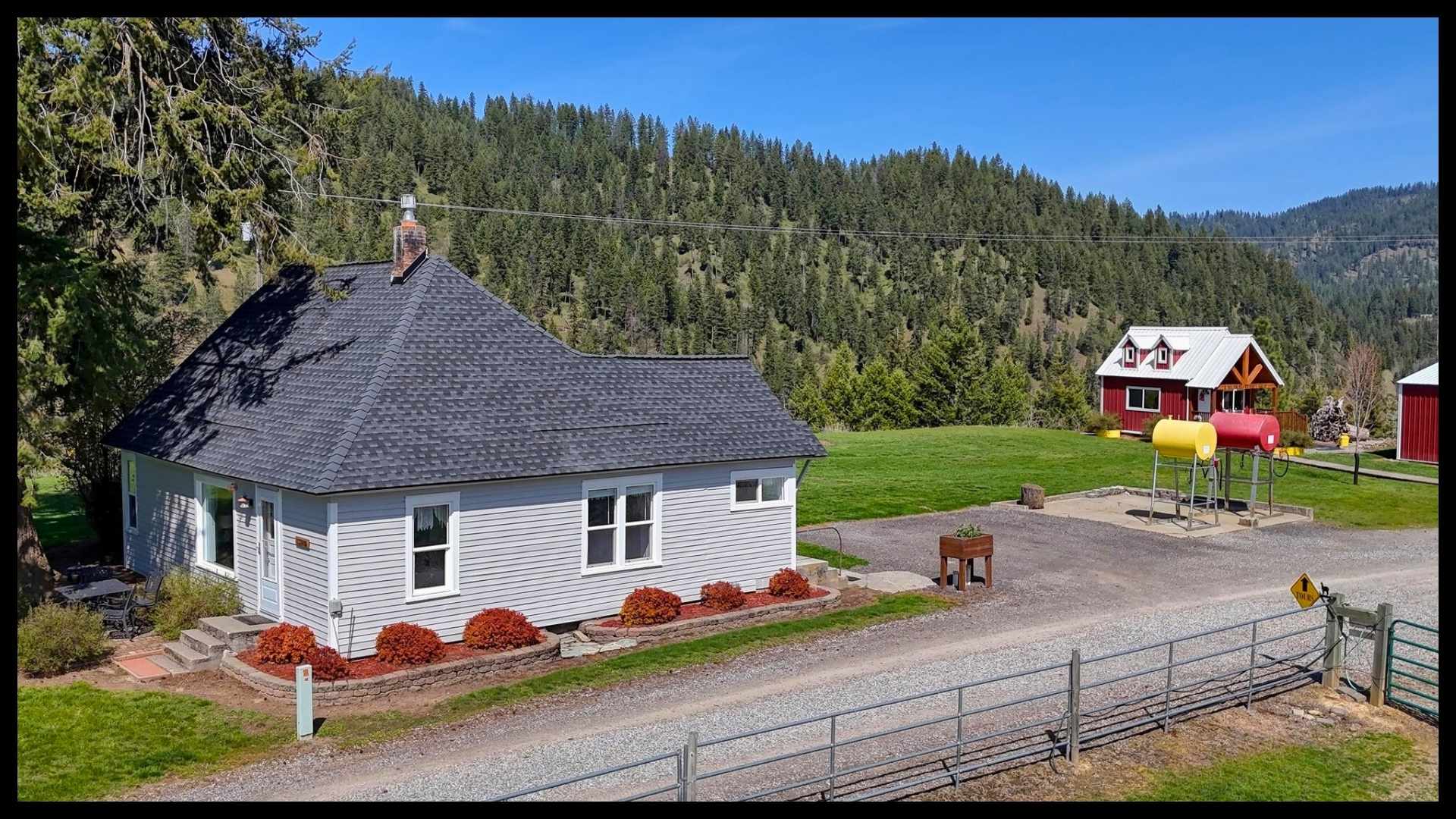 white two-bedroom guest cottage with mountain views at North Idaho ranch, featuring nearby red gift shop opportunity